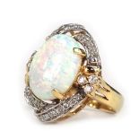 A dress ring, with oval imitation opal, in four claw setting, surrounded by swirl of diamonds, in ye