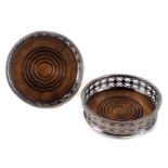 A pair of silver plated wine coaster, each with a pierced and fret border, on turned wooden bases, 1