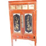 A Chinese red painted cabinet, with an arrangement of two doors, each inset with carved figural lacq