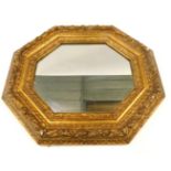 A gilt gesso octagonal wall mirror, the frame decorated with fruit, leaves, scrolls, etc., 65cm x 78