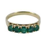 An emerald set dress ring, set with five round brilliant cut emeralds each in claw setting on a yell