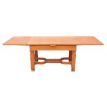 An oak extending dining table, the rectangular top on a moulded X frame base, with carved supports,