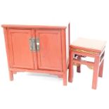 A Chinese red painted cabinet, with two panelled doors, on plain supports with brackets, 78cm high,