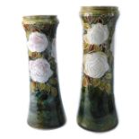 A pair of Royal Doulton stoneware vases, each with a circular top on a green glaze, with white roses