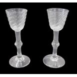 A pair of late 18thC/early 19thC wine glasses, each with a bell shaped wrythen bowl, and a knopped s