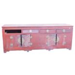 A Chinese red stained elm sideboard or side cabinet, with a plain top above three frieze drawers, an