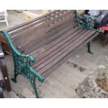A metal ended slatted garden bench, painted in green.