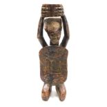 An Africa carved wooden figure of a fertility goddess, modelled in kneeling position, with arms alof