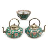 A pair of Chinese porcelain and white metal teapots, decorated with flowers on a green ground, with