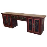 A Chinese red and black lacquer table cabinet, the rectangular top over a pair of central frieze dra