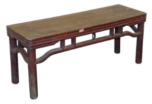A Chinese red lacquered bench, of rectangular section, with a carved frieze, raised on cylindrical l