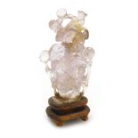 A Chinese quartz snuff bottle and stopper, carved with birds and berries, raised on a wooden stand,