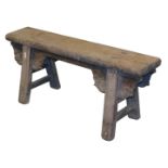 A Chinese wooden bench, raised on trestle end supports, with foliate carved brackets, united by stre