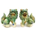 A pair of Chinese green glazed dogs of fo, modelled facing left and right in seated pose, 21cm wide.