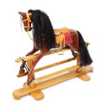 A rocking horse, with a tan leather saddle and bridle, raised on a light oak base, 133cm wide.