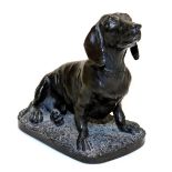 A bronzed resin figure of a Dachshund by David Geenty, modelled seated on an oval base, indistinctly