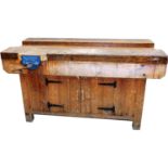 A pine work bench, with a Record No. 52B vice, with cupboards below, 80cm high, 152cm wide, 77cm dee