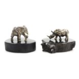 Two miniature figures, modelled as an elephant, and a rhinoceros, each on wooden bases, white metal,