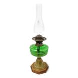 An early 20thC duplex brass oil lamp, embossed with leaves, with a green glass reservoir and clear g