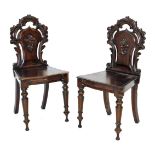 A pair of Victorian oak hall chairs, with pierced floral, foliate and C scroll carved backs, solid s