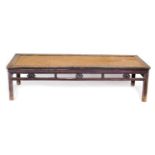 A Chinese hardwood and rattan table, of rectangular form, with a carved galleried frieze, raised on