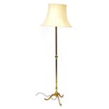 An early 20thC brass standard lamp, raised on three leaf capped cabriole legs, with a cream shade, 1