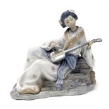 A Nao porcelain figure of a geisha girl, model seated playing a Shamisen lute, printed marks, 29cm w