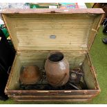 A large metal trunk, with various metalware items inside, including a helmet and a churn.