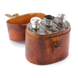A leather travel case, enclosing three cut glass travel bottles, each with a silver stopper. (1 AF)