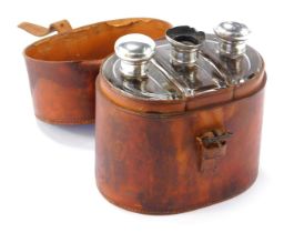 A leather travel case, enclosing three cut glass travel bottles, each with a silver stopper. (1 AF)