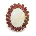 A cluster ring, with oval cut imitation opal surrounded by garnets, in a yellow metal setting, unmar