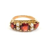 A 9ct gold dress ring, set with three round brilliant cut garnets and four cultured pearls, in a rai