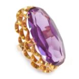 A dress ring, with oval amethyst in claw setting, with three layered fluted shank, yellow metal stam