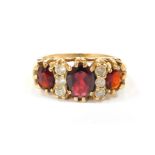 A 9ct gold dress ring, set with three oval garnets, and six imitation diamonds, in a raised claw set