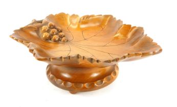 A Black Forest pine musical dish, carved as a vine leaf with grapes, on a circular base, with musica