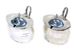 A pair of Edward VII silver mustard pots, with hinged lid, blue glass liner, Sheffield 1909, 8.4oz.