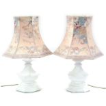 A pair of white ceramic table lamps, each with brass fittings, and an Oriental style shade, the lamp