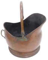 A helmet shaped copper coal scuttle with swing handle and moulded foot.