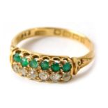 An 18ct gold dress ring, the head channel set with emeralds and diamonds, in claw setting with scrol
