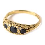 A 9ct gold gypsy ring, the channel set with three sapphires, and four tiny diamonds, with scroll set