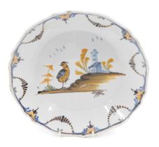 An 18thC La Rochelle Faience plate, decorated with a bird, church, etc., 23cm diameter.