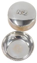 Two items of white metal, comprising a pill box, with beaded border, bearing the initials NZ, white