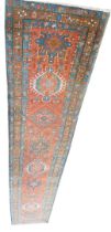 A Persian runner, with a design of medallions, on a red ground with three narrow borders, 91cm wide,