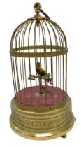 An early to mid 20thC Swiss style musical bird cage, with yellow and black bird seated on a perch, t