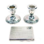 A small silver Art Deco cigarette case, Birmingham 1929, 3.62oz, and a pair of dwarf candlesticks, e