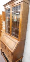 An oak bureau bookcase, with stained glass panelled doors, on barley twist column supports.