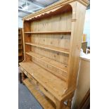 A pine kitchen dresser, with a three shelved top, on sideboard base with three drawers and open shel