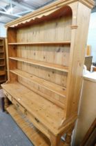 A pine kitchen dresser, with a three shelved top, on sideboard base with three drawers and open shel