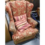 A wingback armchair, red and gold floral upholstery.