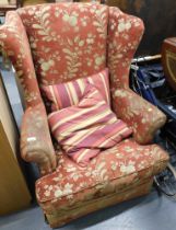 A wingback armchair, red and gold floral upholstery.